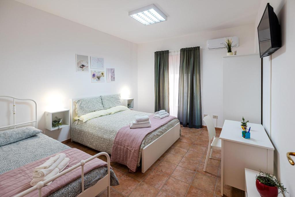 a bedroom with two beds and a desk and a television at Casa Del Corso in Motta Camastra