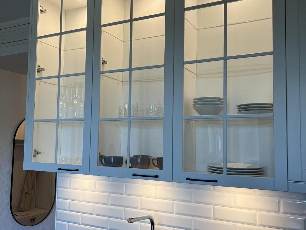 a kitchen with blue glass cabinets with dishes inside at A comfortable apartment for 3 people in Pobierowo in Pobierowo