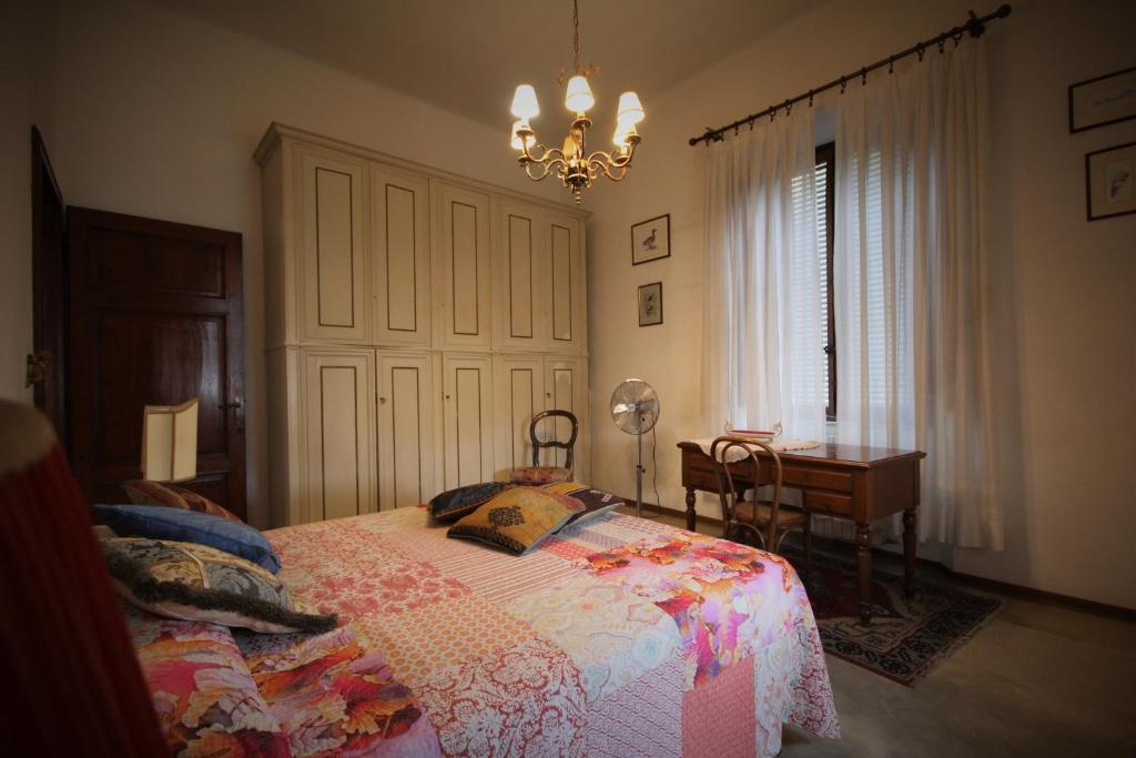 een slaapkamer met een bed, een bureau en een kroonluchter bij Primo piano villa liberty indipendente a Lucca in Lucca