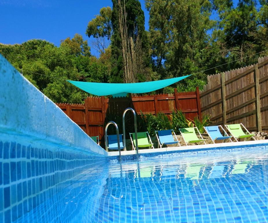 a swimming pool with lounge chairs and a blue umbrella at Complejo Rural Huerta Grande in Algeciras