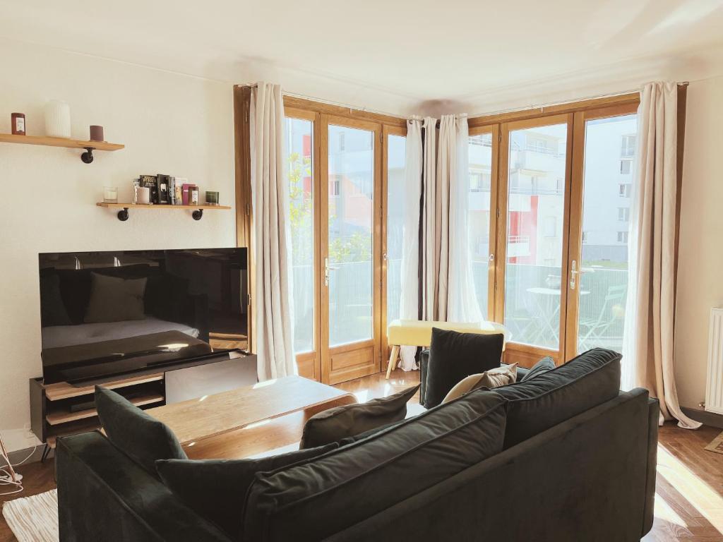 salon z czarną kanapą i telewizorem w obiekcie Les Clairières - spacieux T3 tout à pied w Annecy