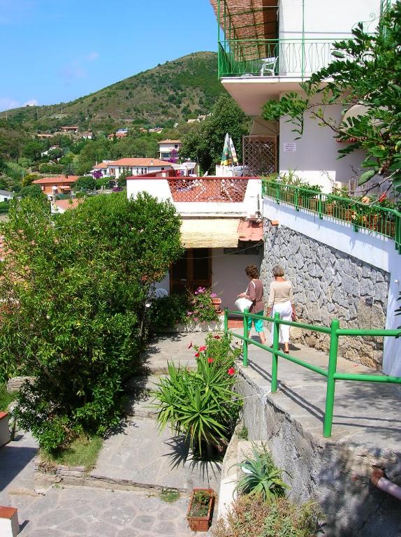 two women sitting on a bench in front of a building at Hotel Alma in Campo nell'Elba