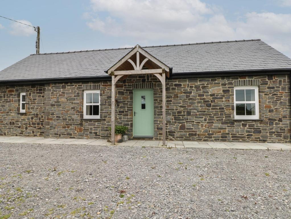 a stone building with a green door in front of it at Ystabl Robyn in Carmarthen