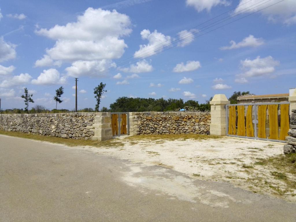 a stone fence with yellow doors and a stone wall at Masseria Petrore Grande di Polimeno Alessandra in Cutrofiano
