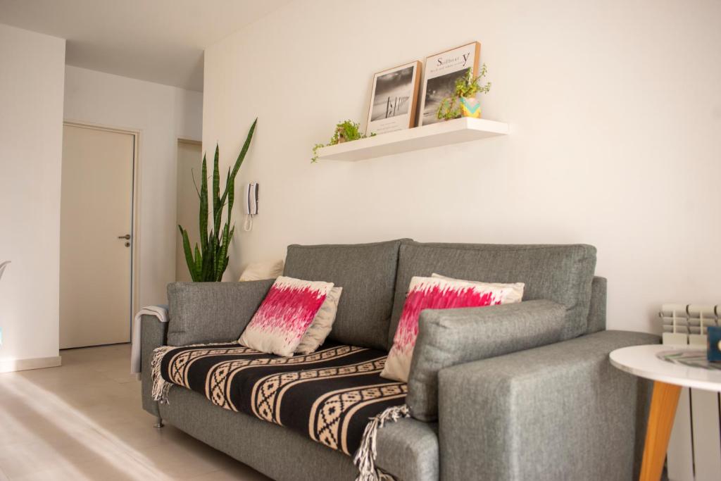 sala de estar con sofá gris y almohadas rosas en Departamento Premium con cochera y piscina en Bahía Blanca