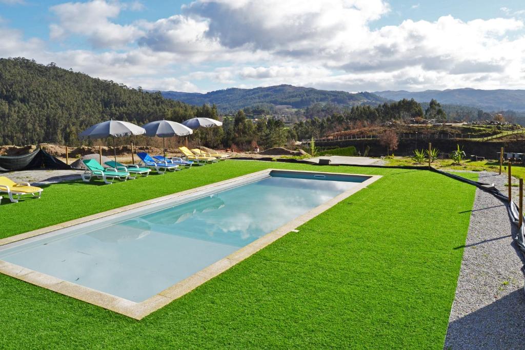 uma piscina com cadeiras e guarda-sóis num relvado em Campo Seco em Vieira do Minho