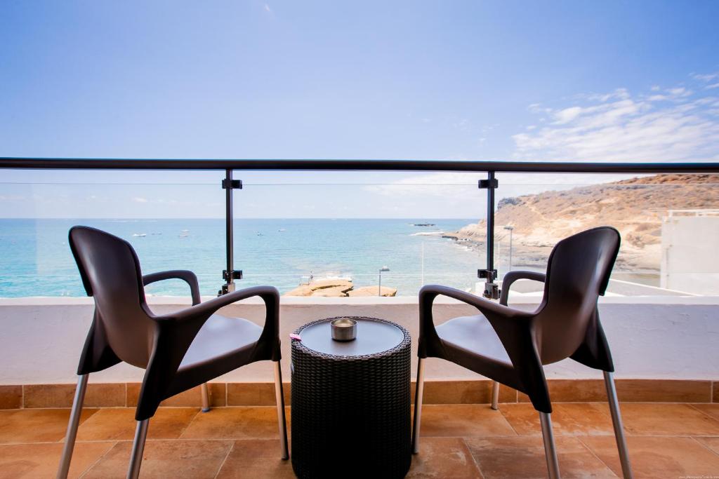 - deux chaises et une table avec vue sur l'océan dans l'établissement Apartments La Caleta Sunrises, à Adeje