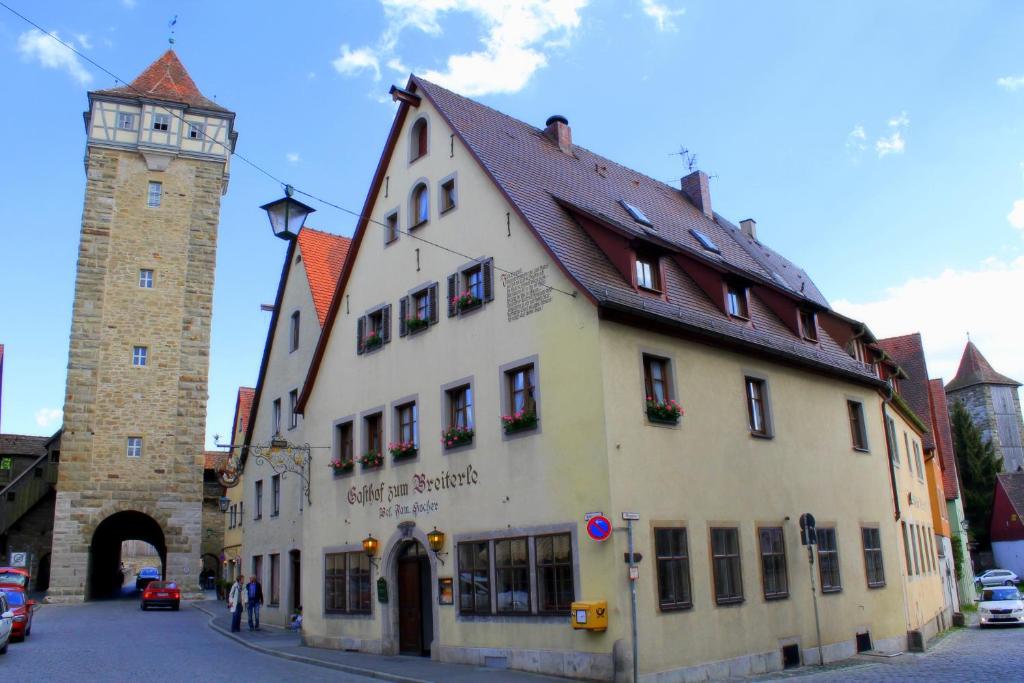 un grand bâtiment blanc avec une tour d'horloge dans une rue dans l'établissement Hotel Zum Breiterle, à Rothenburg ob der Tauber