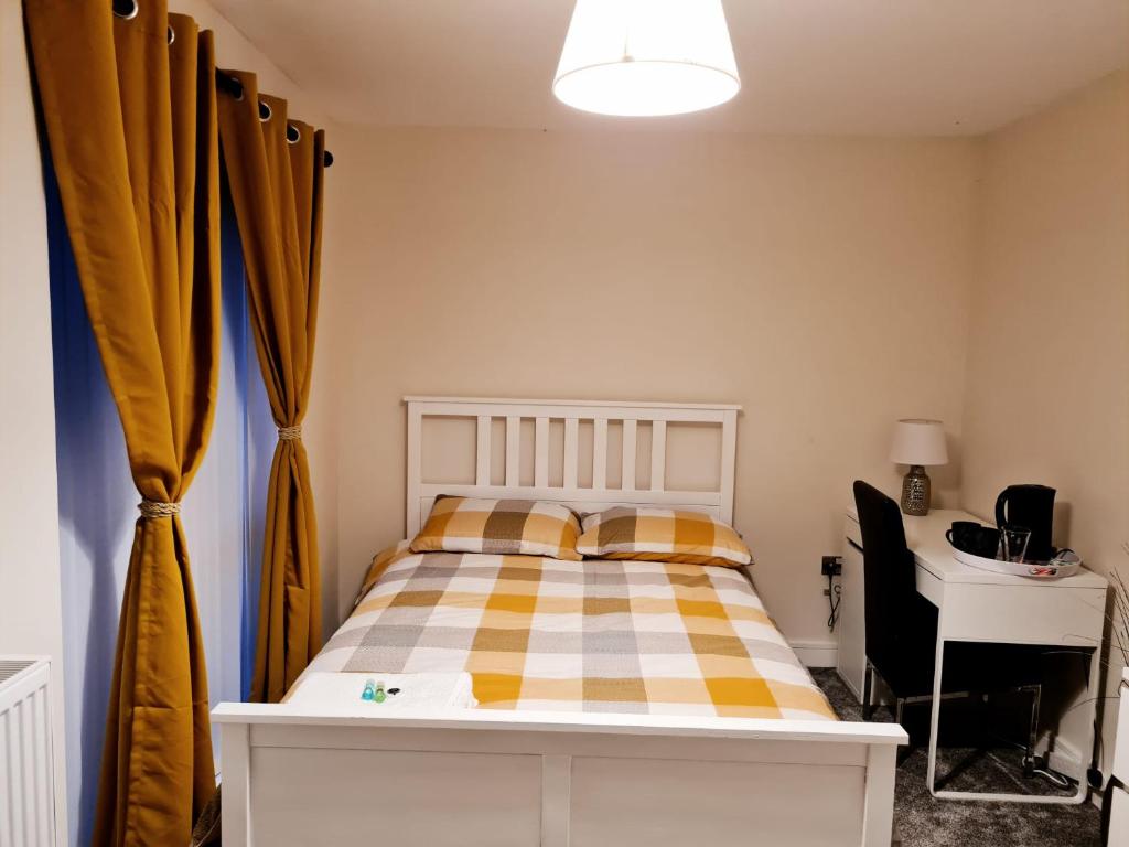 a bedroom with a bed and a desk and curtains at Mills Home Stays in Derby