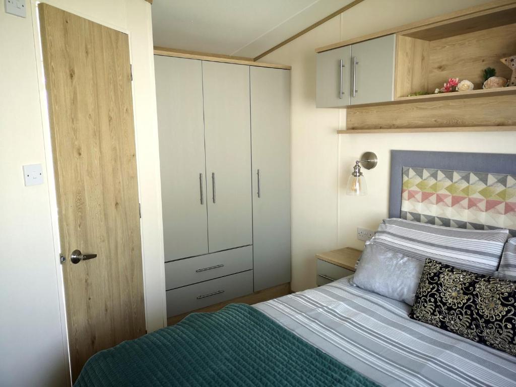 a small bedroom with a bed and a cabinet at Lake Escape - Hoburne Cotswolds in South Cerney