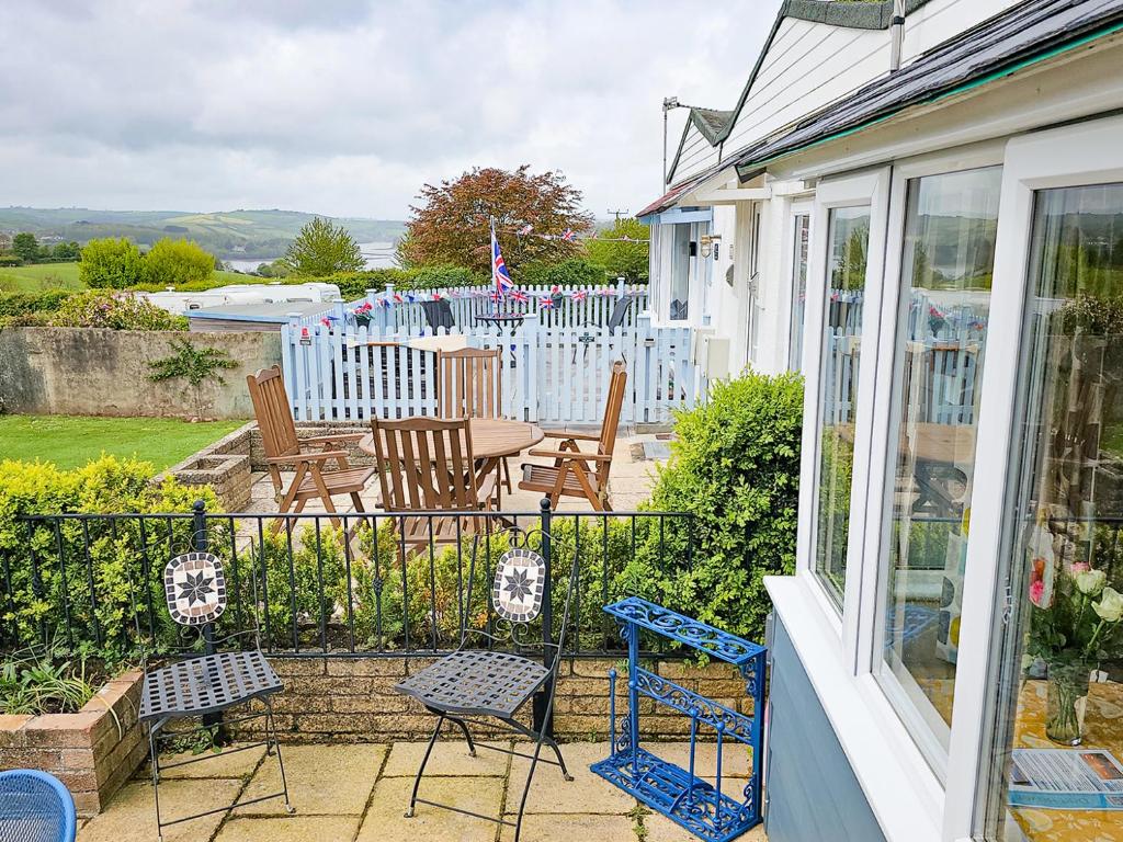 a porch of a house with chairs and a table at Dart Haven - cheerful holiday bungalow in Galmpton in Galmpton-on-the-Dart