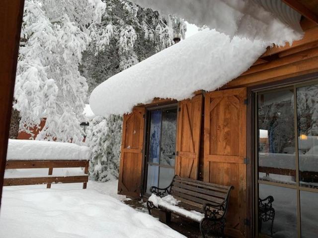 um telhado coberto de neve de uma cabina com um banco em Cabaña en Termas de Chillán em Pinto