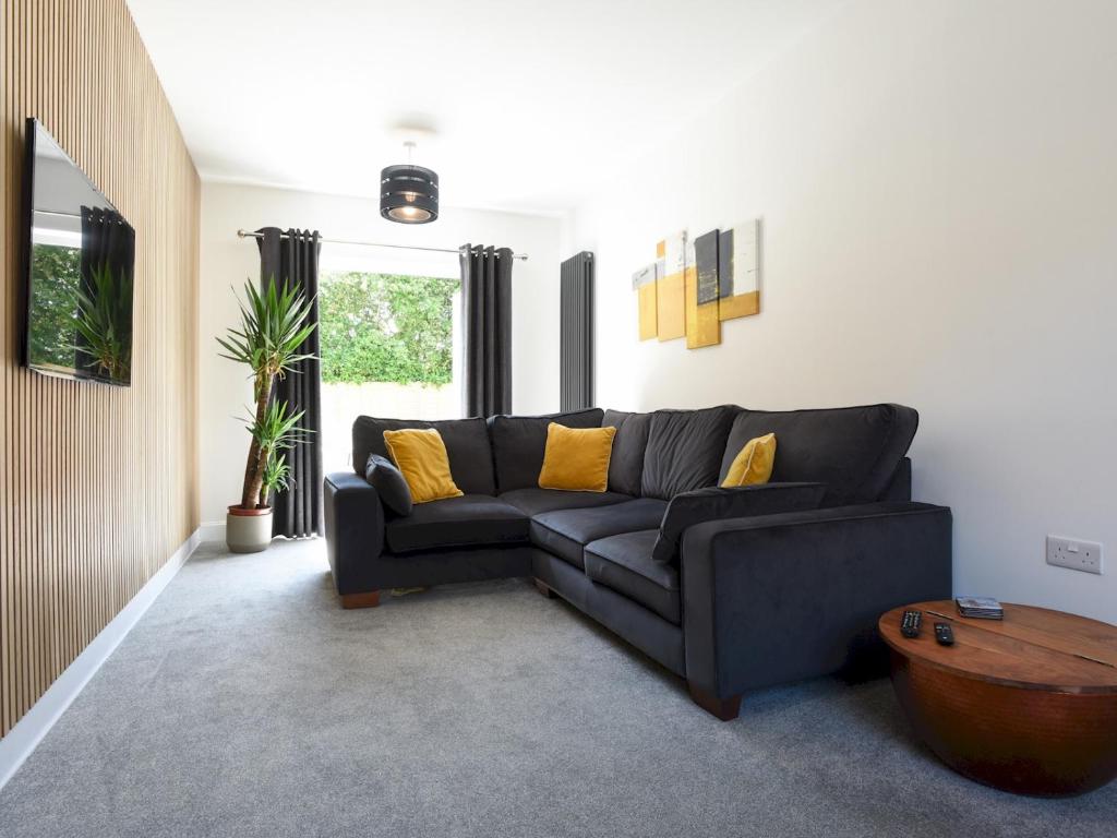 a living room with a black couch and yellow pillows at Pass the Keys Beautiful Family Home Sleeps 6 in Emsworth