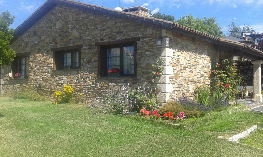 una casa de piedra con flores delante en Ruta Del Aguila alojamiento turístico de calidad en Santa María de la Alameda