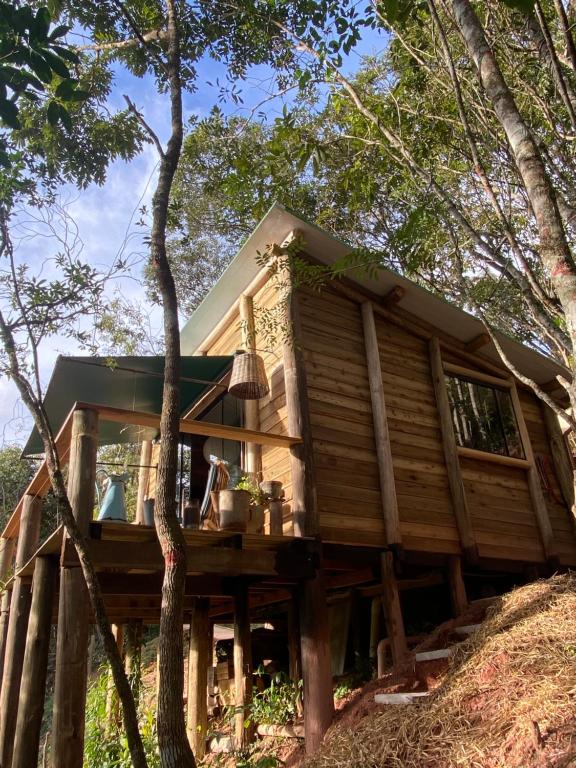 ein Baumhaus mit einer Terrasse im Wald in der Unterkunft Reserva Jacarandá Cabanas in Aiuruoca