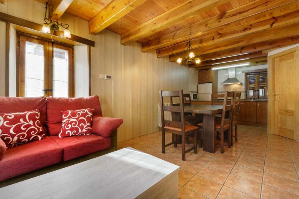a living room with a red couch and a table at Casitas centro panticosa in Panticosa
