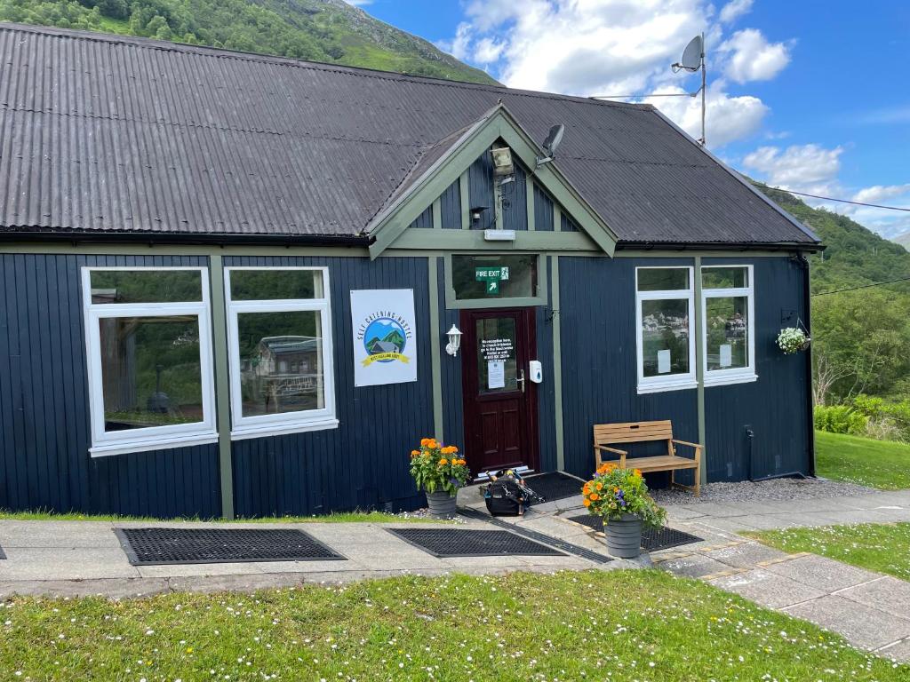um edifício azul com um banco à frente em West Highland Lodge em Kinlochleven