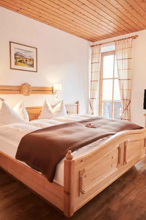 a large wooden bed in a room with a window at Haus Ranker in Reit im Winkl