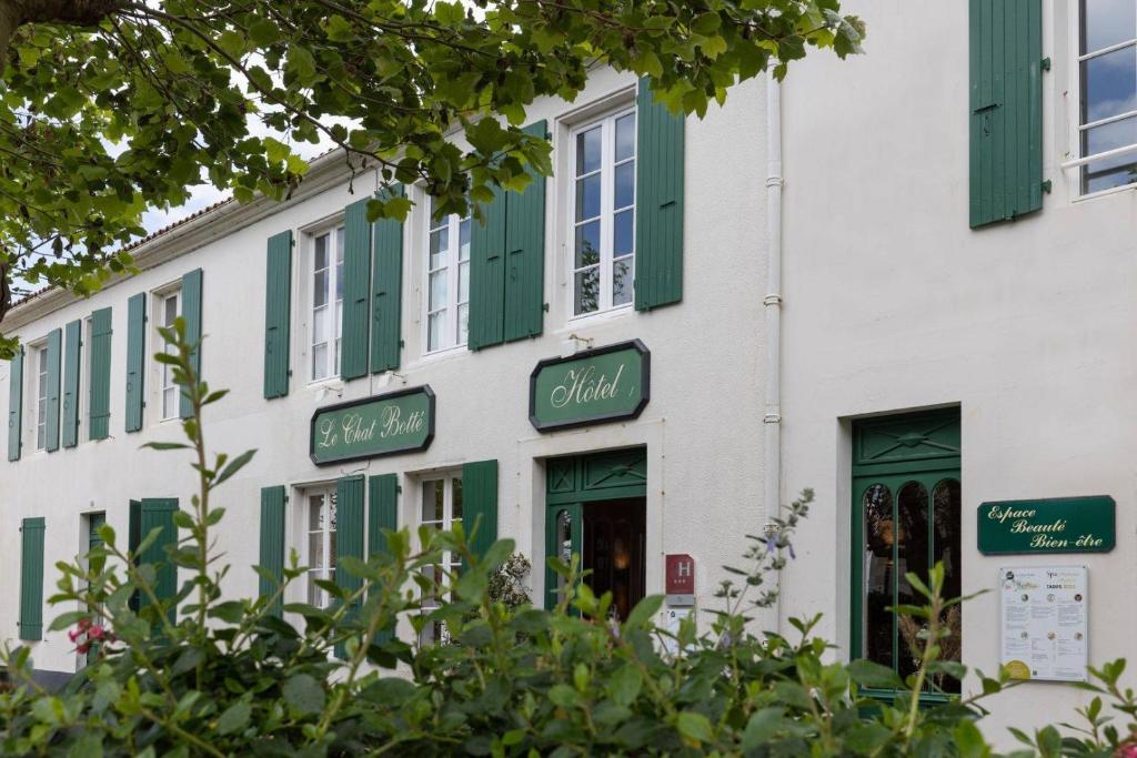un edificio blanco con persianas verdes. en Le Chat Botté en Saint-Clément-des-Baleines