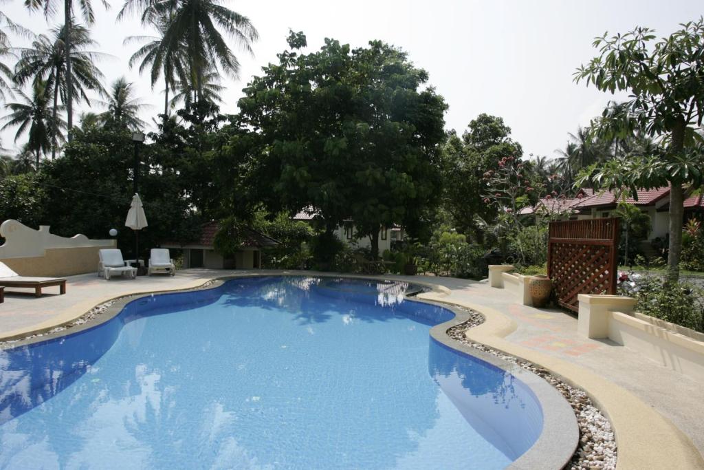 a large blue swimming pool with trees in the background at Reuan Phaolai in Bophut