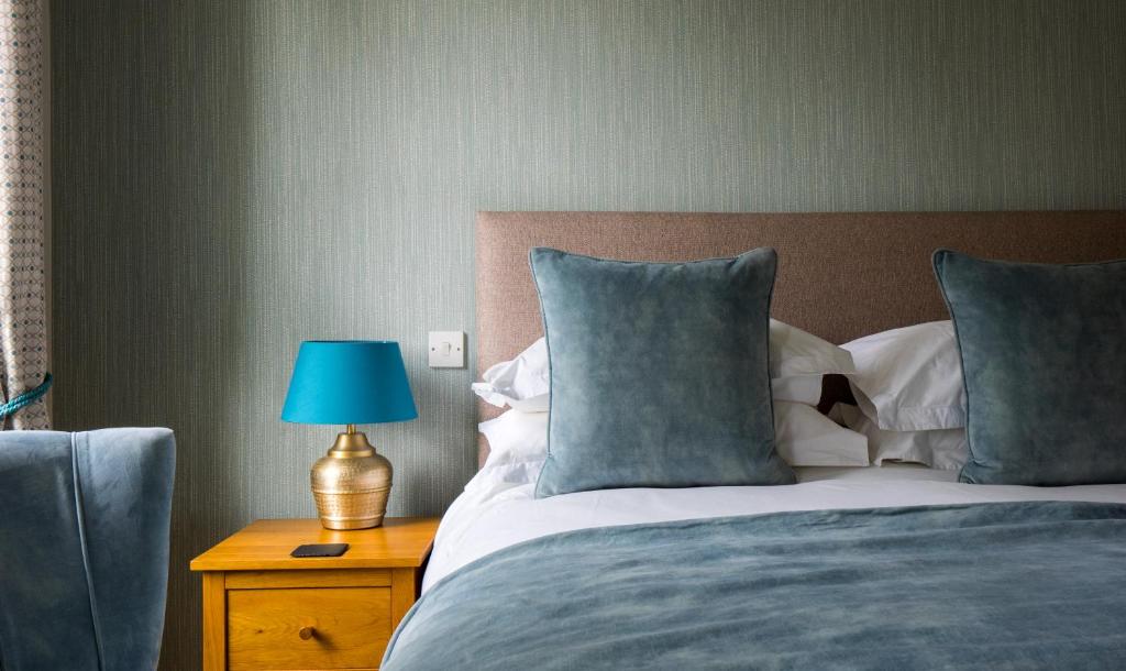 Una cama con almohadas azules y una lámpara azul en una mesa. en Chestnuts House Boutique B&B, en Bath