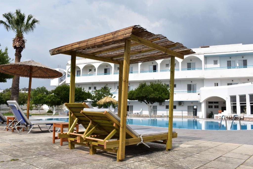 een groep stoelen en parasols naast een zwembad bij Manos Pension in Faliraki