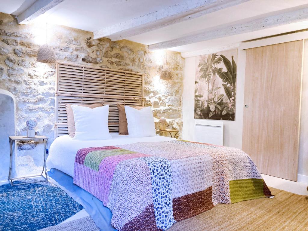 - une chambre avec un lit et un mur en pierre dans l'établissement Résidence du Platane, à Saint-Laurent-des-Arbres