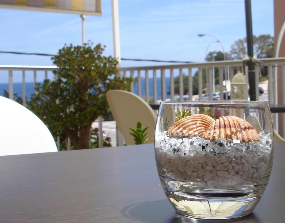 um copo cheio de areia e conchas numa mesa em Pensión El Hidalgo em Calpe