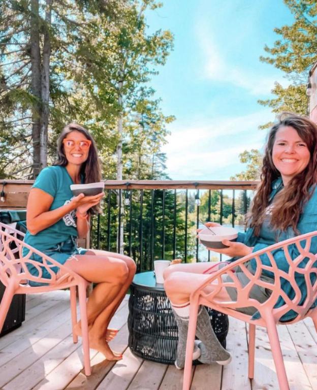 two women sitting on a deck with a tablet at Flora Studio on the Lake in Saint Martins