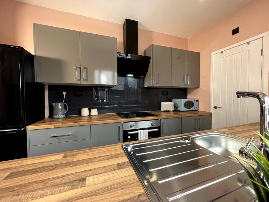 a kitchen with stainless steel appliances and wooden floors at Modern and spacious house with Hot Tub in Lincolnshire