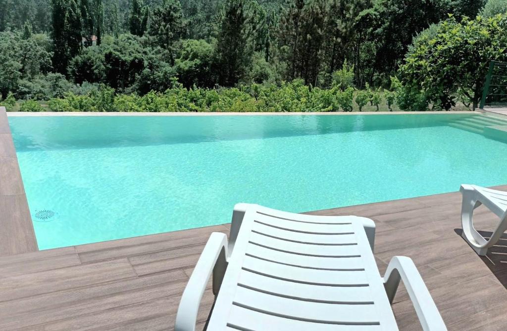 a white chair sitting next to a swimming pool at Casa da Costureira in Olival