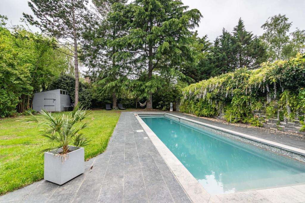 ein Pool neben einem Garten mit Bäumen in der Unterkunft Villa des Puits - Welkeys in La Celle-Saint-Cloud