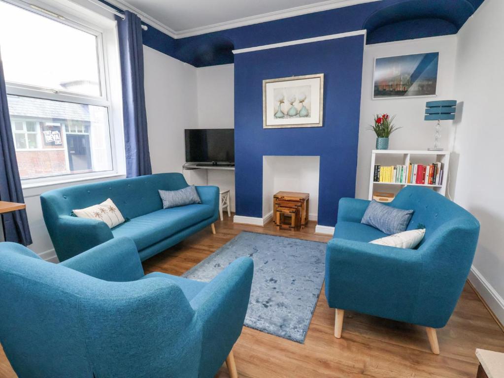 a living room with blue chairs and a blue wall at Oneofour in Chester