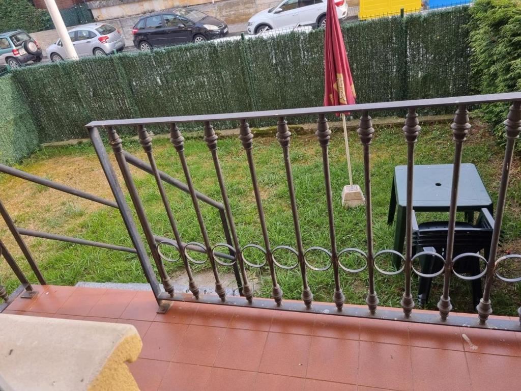 a rail on a balcony with a table and an umbrella at Bajo con Jardin en Cartes in Cartes