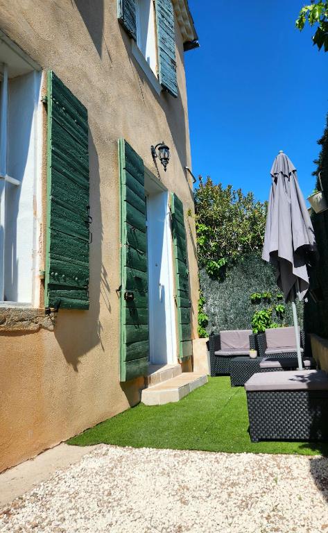 un edificio con persianas verdes y sombrilla en Appartement de charme avec terrasse, en Toulon