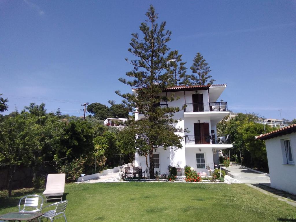 una casa blanca con un árbol en el patio en Villa Ourania en Troulos