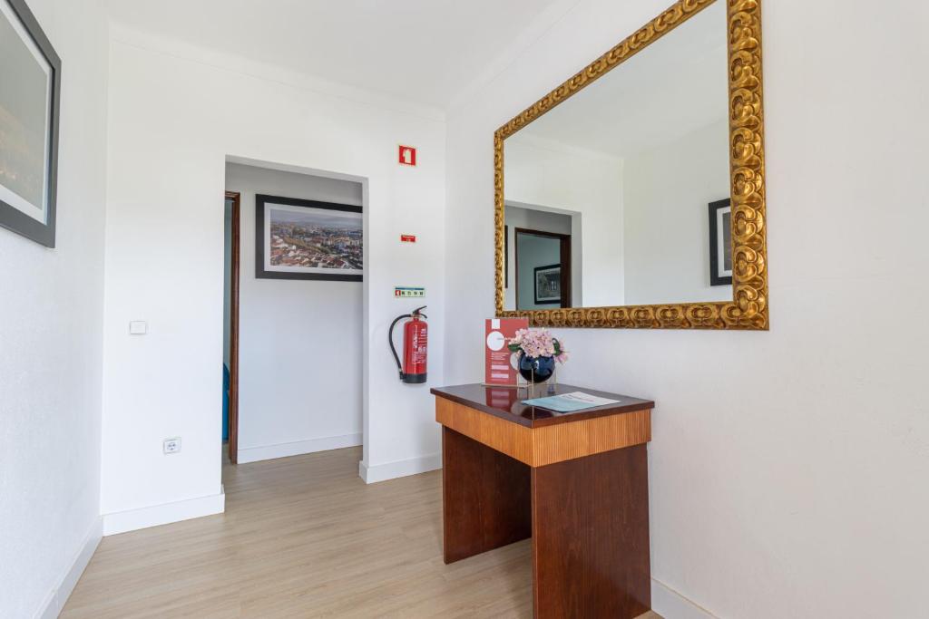 um espelho numa parede num quarto com uma secretária em Guest House Ribeirinho - Alojamento local em Miranda do Corvo