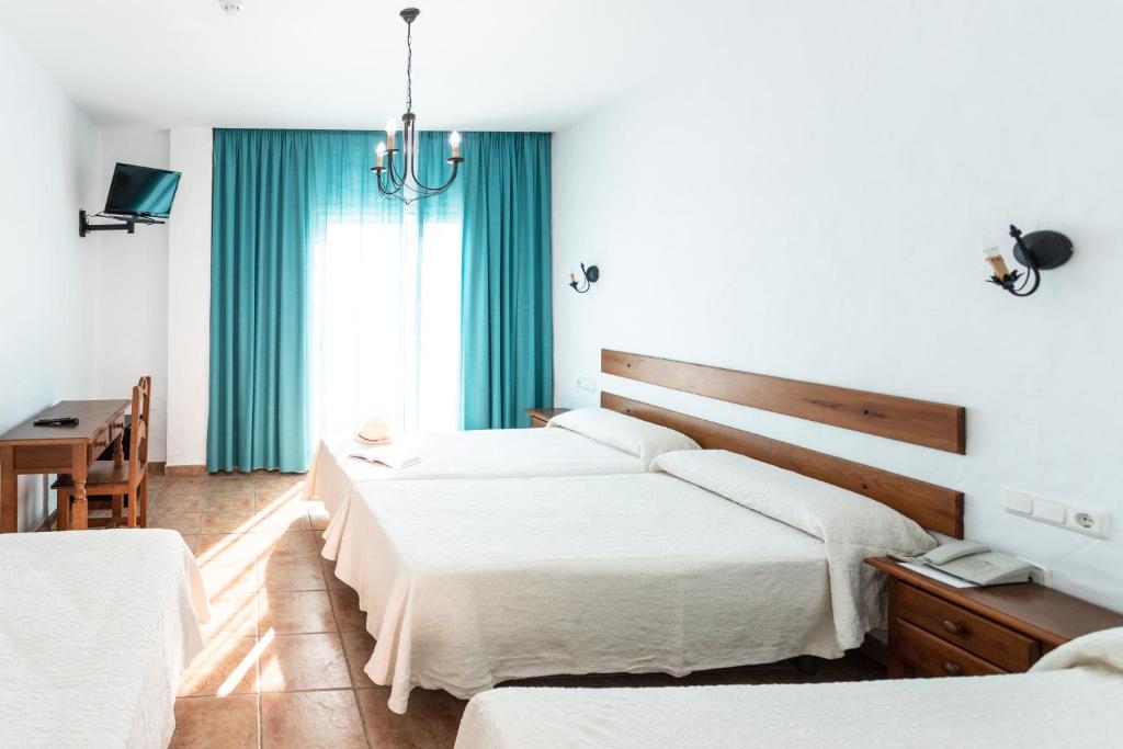 a bedroom with two beds and a desk and a window at Hotel Oasis Atalaya in Conil de la Frontera