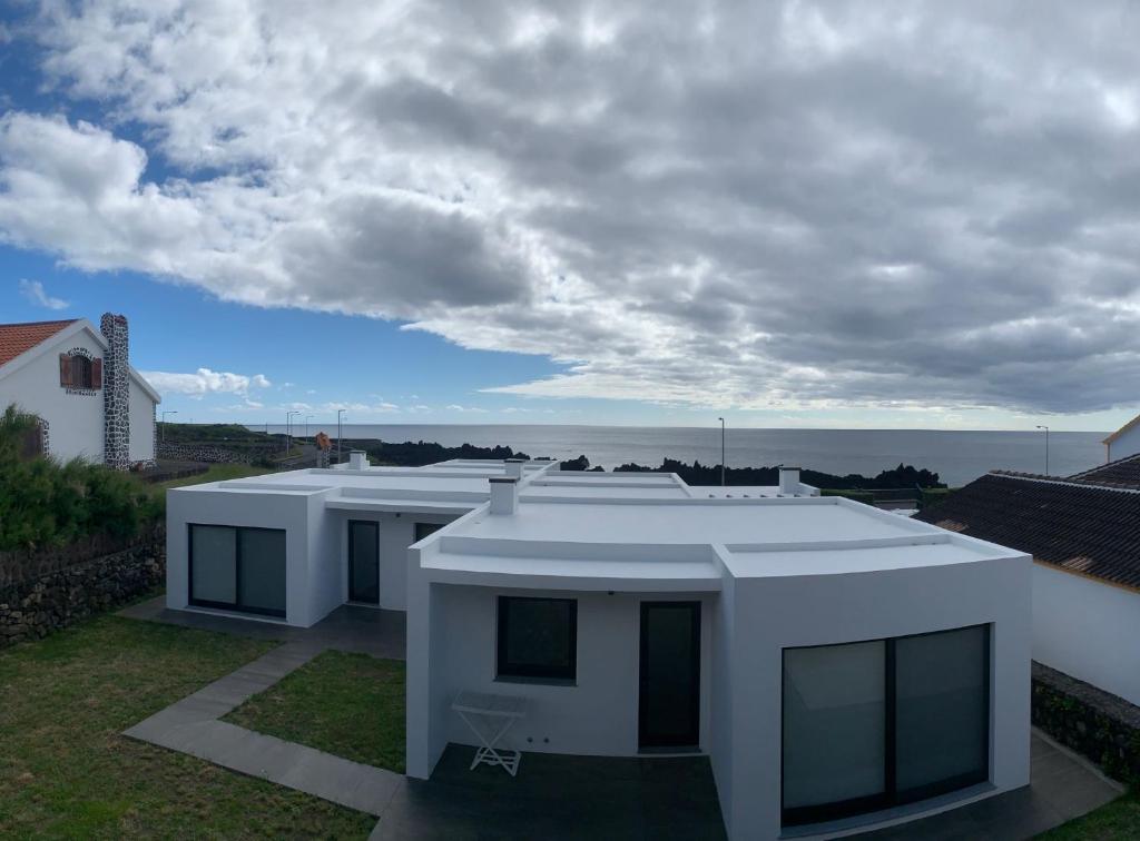 een wit huis met uitzicht op de oceaan bij Fonte da Via in Faja Grande