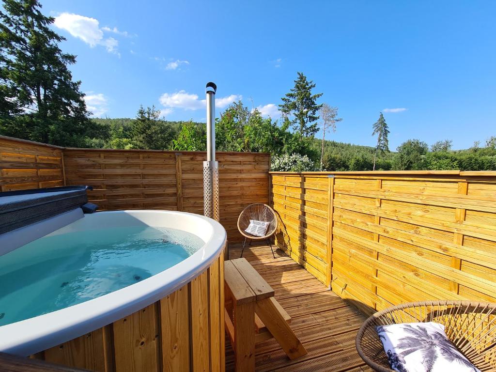 a hot tub on a deck with a wooden fence at Gîte Le Bijou et Spa in Weiterswiller