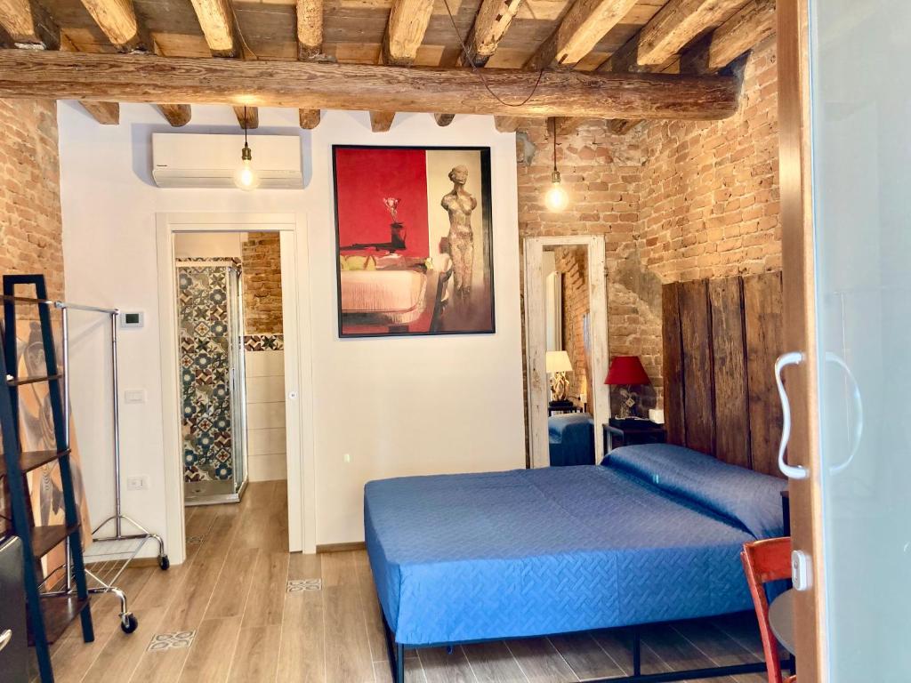 um quarto com uma cama azul e uma parede de tijolos em Old town Chioggia apartments em Chioggia