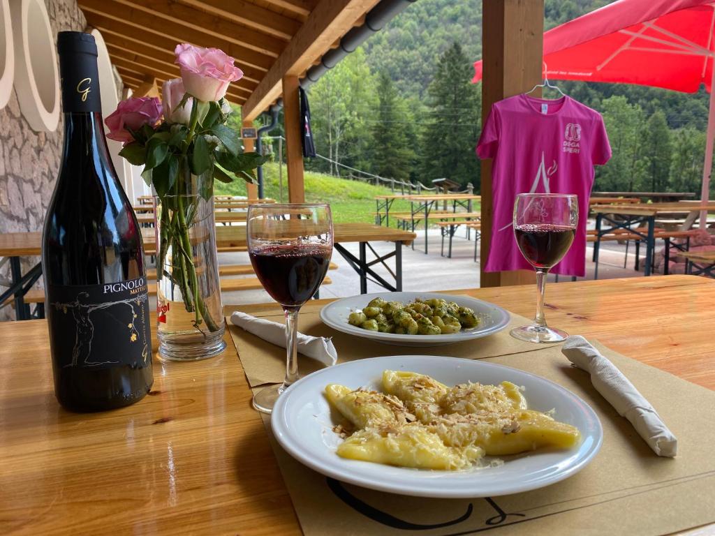 - une table avec deux assiettes de nourriture et deux verres de vin dans l'établissement Rifugio Pian dei Ciclamini, à Lusevera