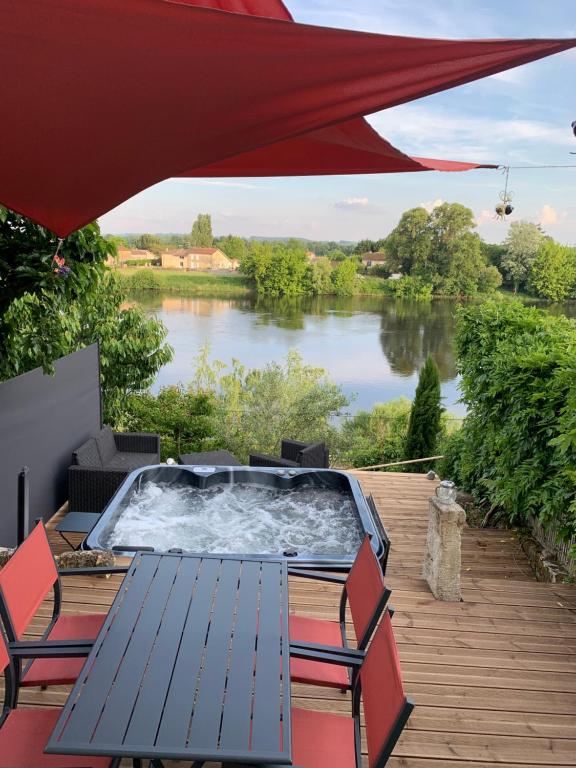 a hot tub on a deck with a view of a river at Maison cocoon avec jacuzzi privé vue Dordogne in Castillon-la-Bataille