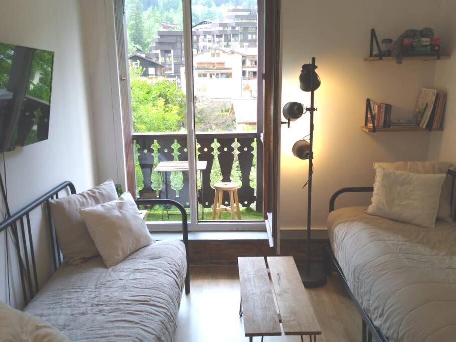 ein Wohnzimmer mit einem Sofa, einem Tisch und einem Fenster in der Unterkunft Studio élégant à Chamonix in Chamonix-Mont-Blanc