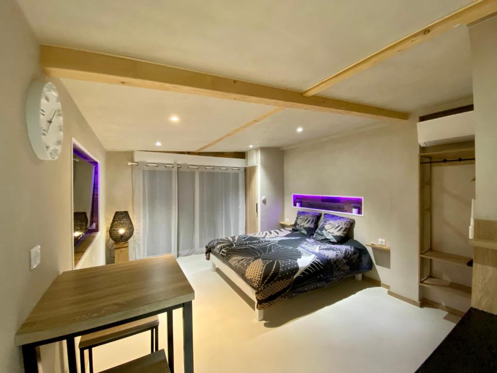 - une chambre avec un lit, une table et un éclairage violet dans l'établissement LE COTTAGE Zen LOVE, à Foucherans