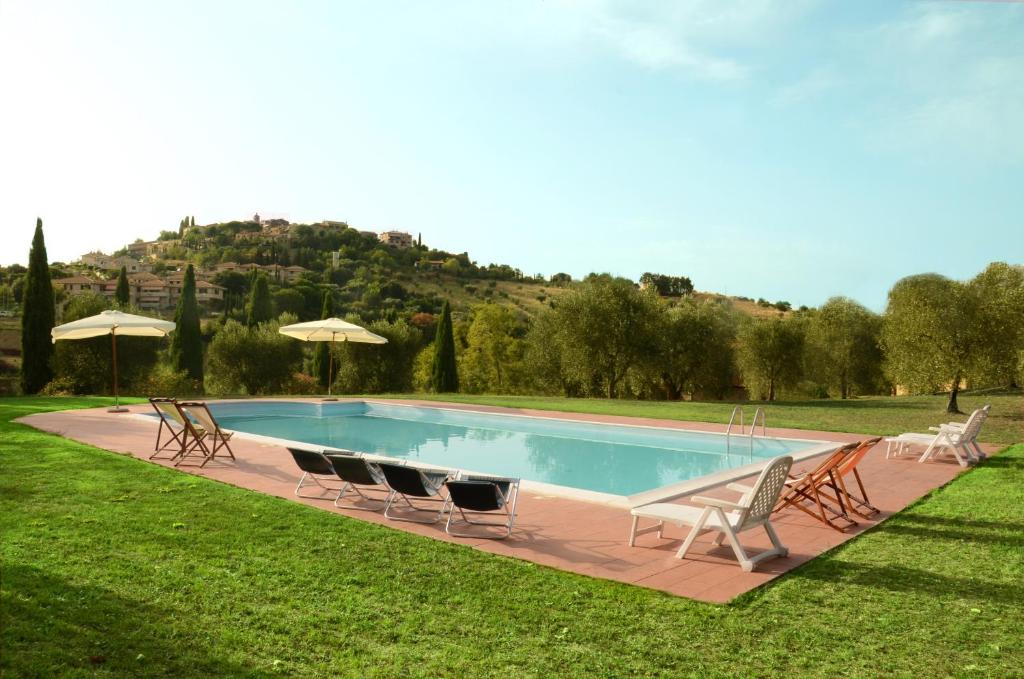 a swimming pool with chairs and umbrellas in the grass at Agriturismo La Fontaccia in Montiano