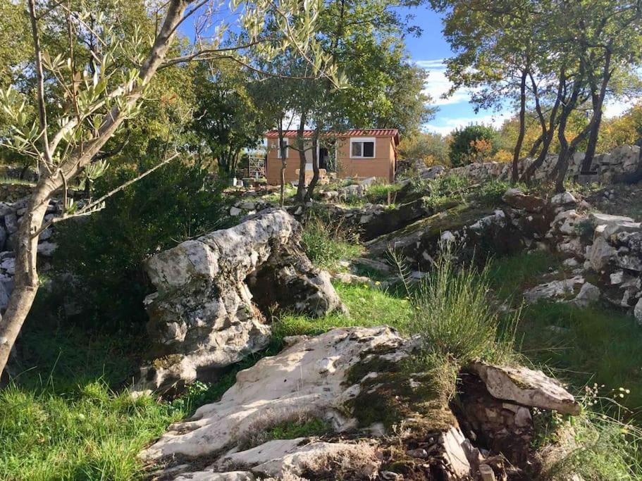 a rock garden with a house in the background at Tiny house & Glamping tent in Kotor