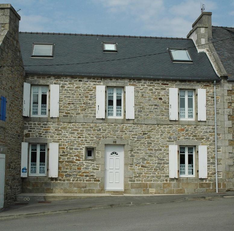 - un bâtiment en pierre avec une porte blanche et des fenêtres dans l'établissement Villa Ropartz, à Roscoff
