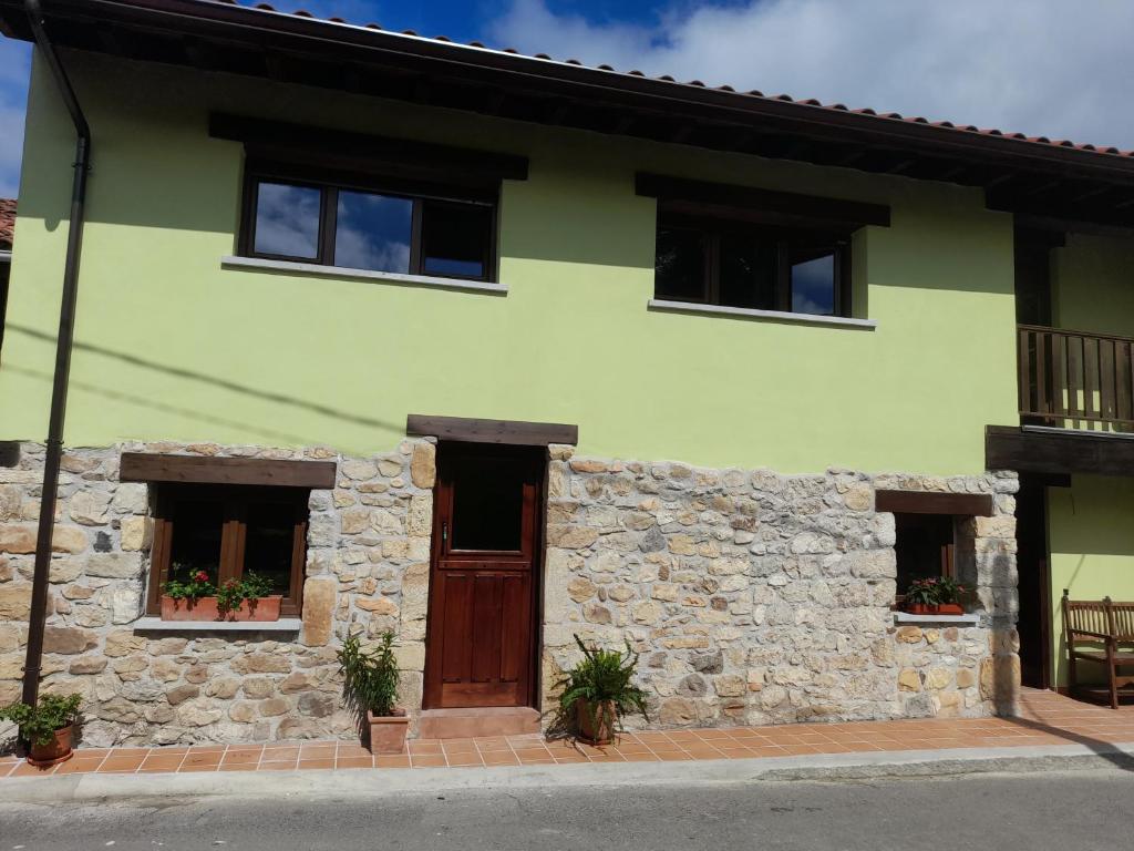 a green house with a stone wall at La Posada del Canario in Cangas de Onís