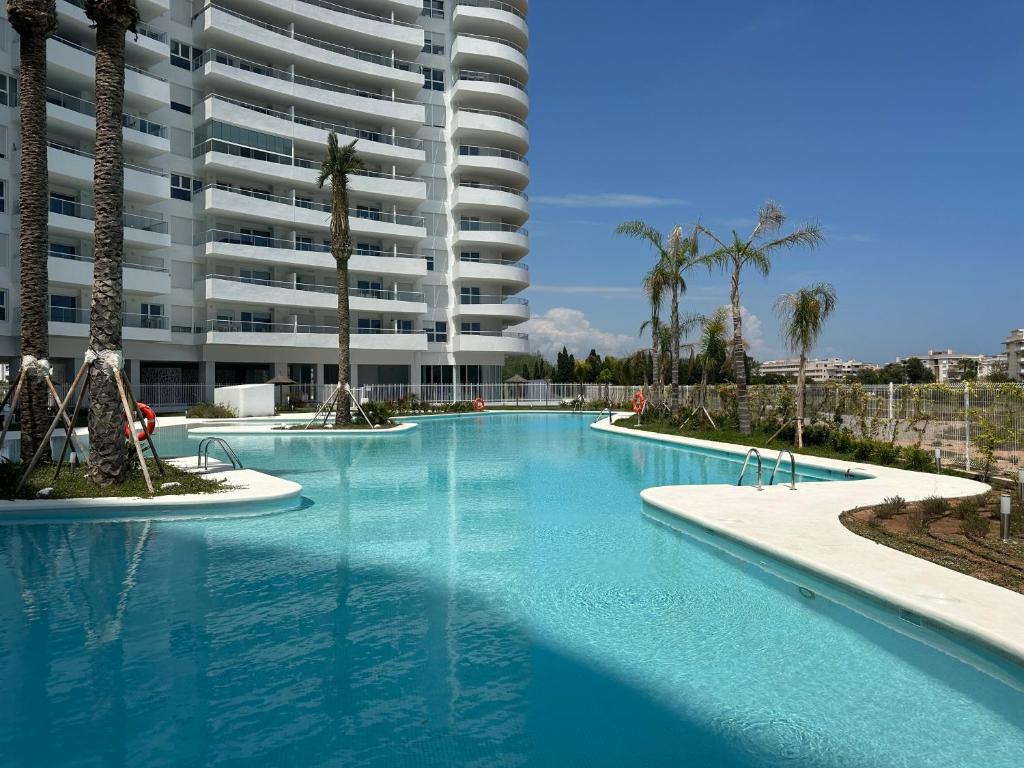 uma grande piscina em frente a um grande edifício de apartamentos em LUXURY Apartaments Gran Canet em Canet d'En Berenguer